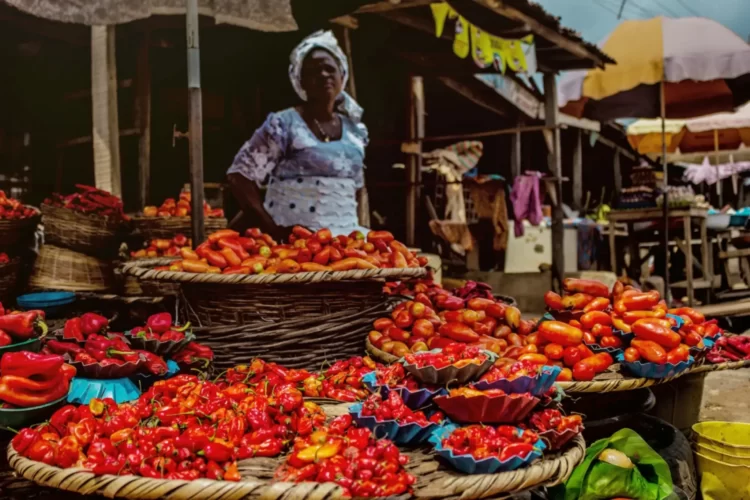 Woman selling pepper sits over her wares in a market